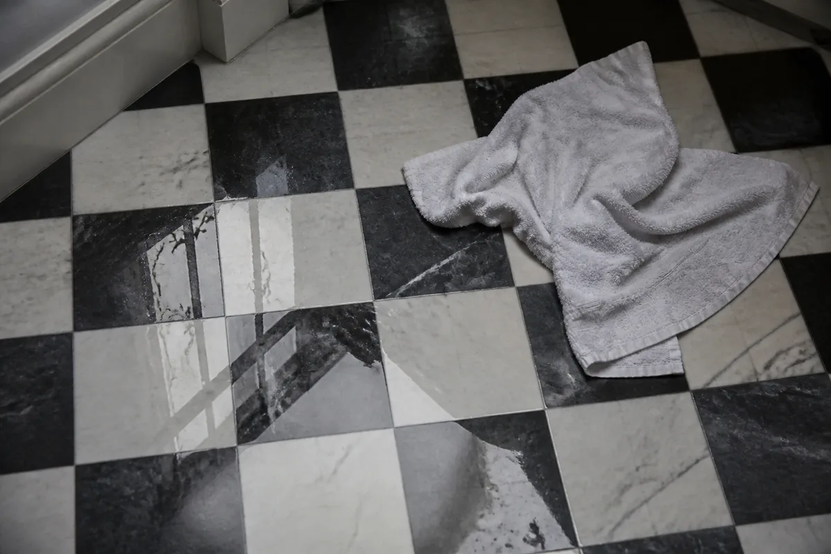 Flaque d&rsquo;eau sur le carrelage d&rsquo;une salle de bain d&rsquo;immeuble ancien