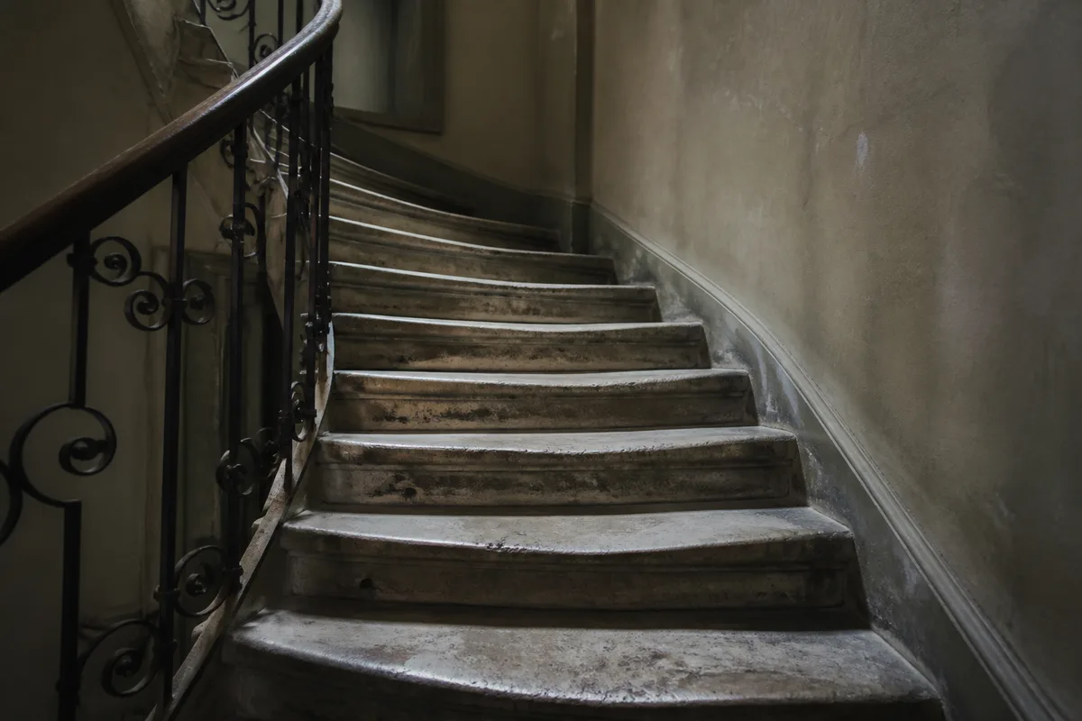Escalier de pierre ancien montant vers une lumière froide