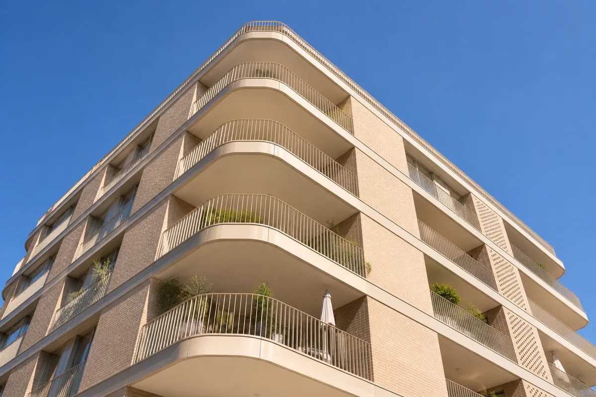 Façade d’immeuble en brique claire vue en contre-plongée sous un ciel dégagé